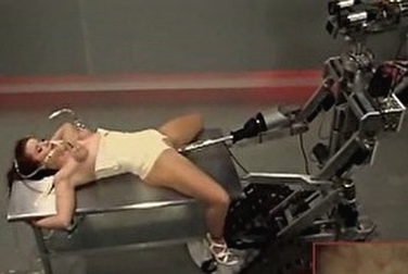 Робот трахает связанную брюнетку на столе